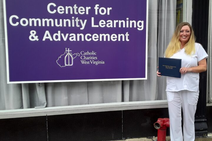 Debra Bunch, dressed in her graduation whites, holds her Licensed Practical Nurse diploma