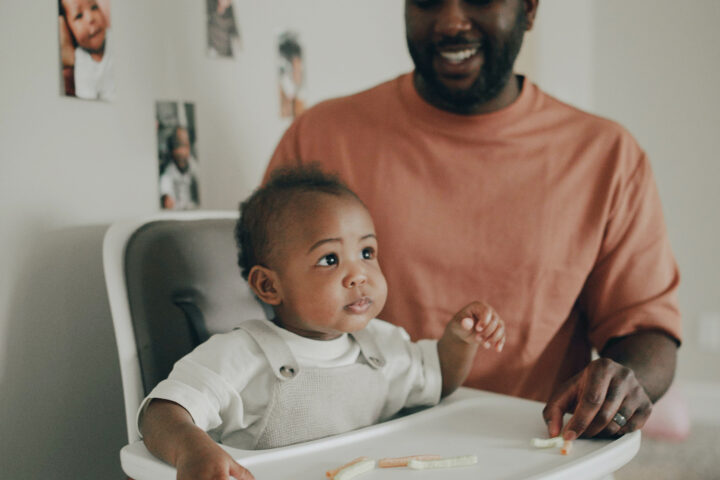 photo of father feeding child in highchair